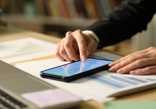 Close up of entrepreneur woman hands signing contract on smart phone with finger at night